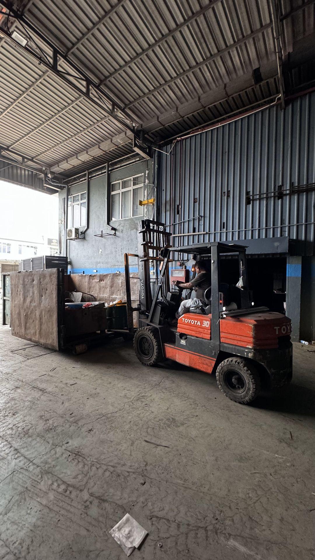 Warehouse interior with a forklift moving a large wooden crate.